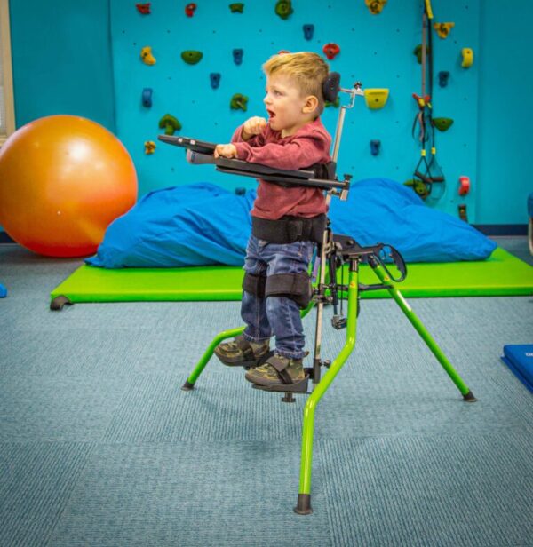 Zing Portable Stander with a boy standing playing in an activities room.