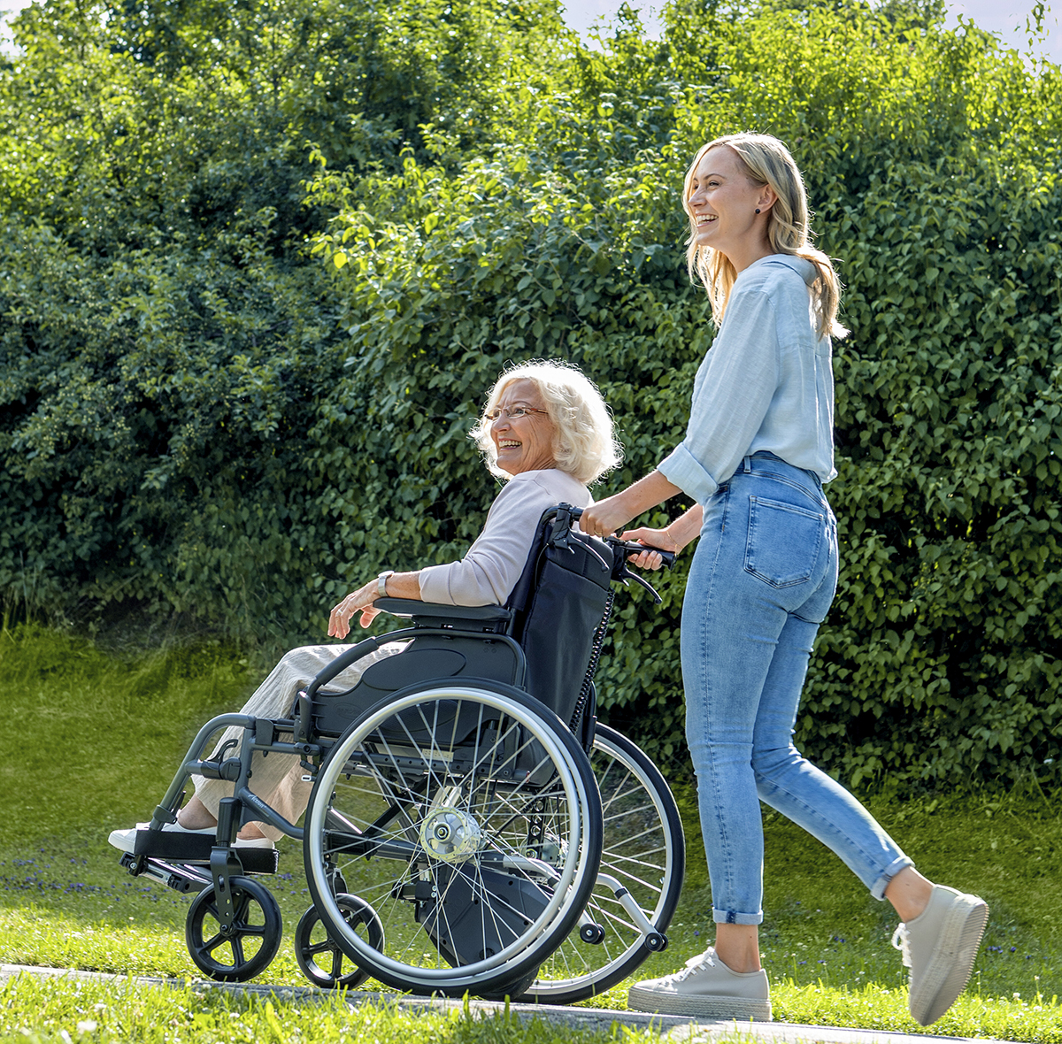 Alber Via Go wheelchair power assist on a wheelchair used by an elderly lady being pushed by a younger lady.
